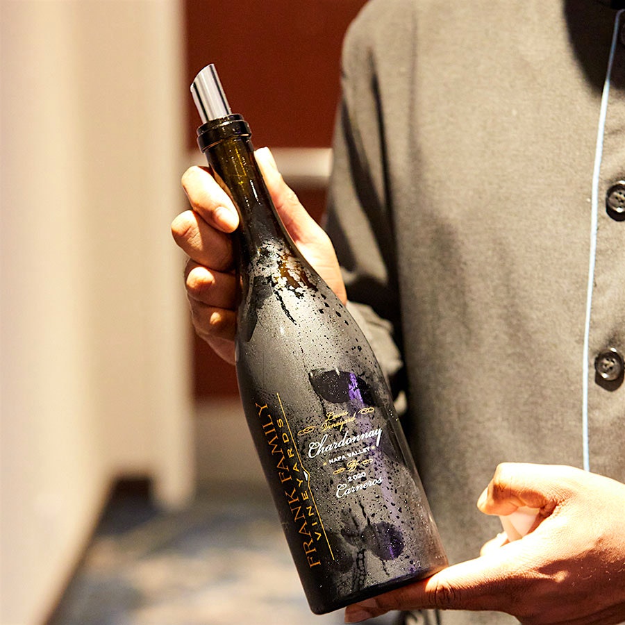 A server holding up a bottle of Frank Family Chardonnay Napa Valley Carneros Lewis Vineyard 2020